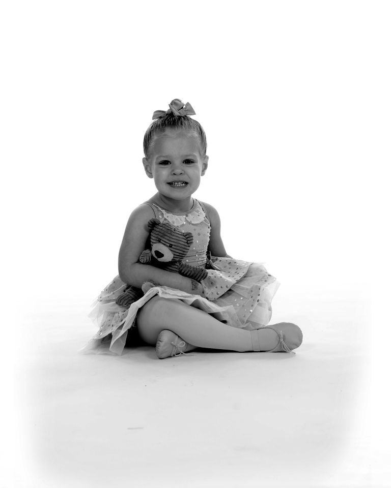 A toddler in a lilac tutu sitting with a stuffed bunny