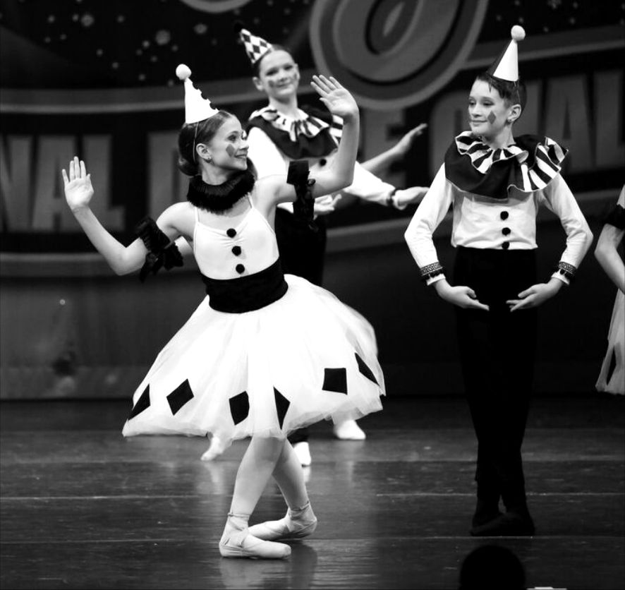 Dancers in black-and-white Pierrot costumes performing on a competition stage