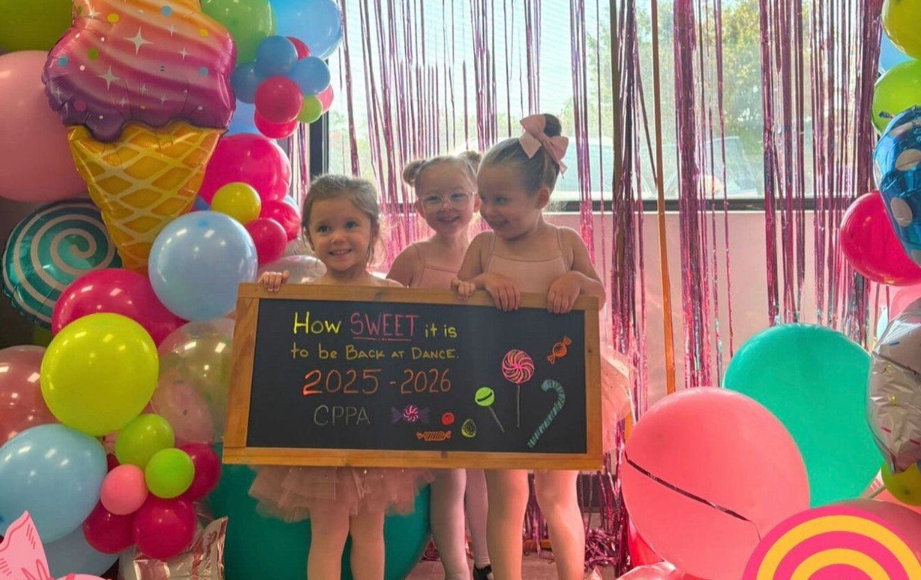 Young dancers holding a chalkboard that reads &ldquo;How sweet it is to be back at dance, 2025&ndash;2026&rdquo;