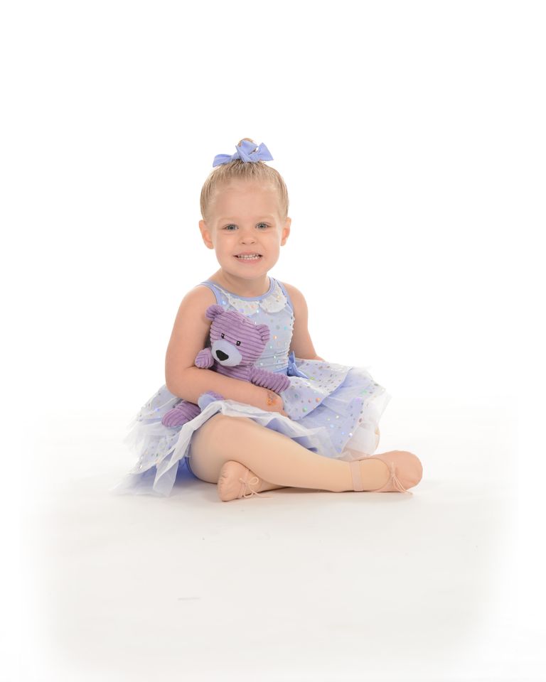 A toddler in a lilac tutu sitting with a stuffed bunny