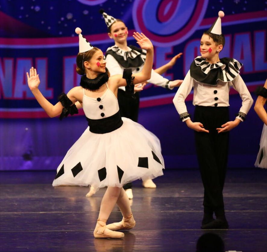 Dancers in black-and-white Pierrot costumes performing on a competition stage
